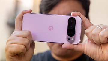 A person holding a Google Pixel 9 Pro smartphone, displaying its pink back and camera setup.