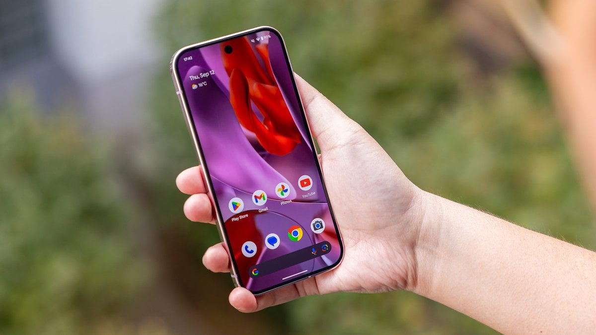 Une personne tenant un smartphone Google Pixel 9 Pro affichant un écran d'accueil coloré.