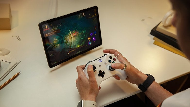 Seseorang sedang bermain permainan pada Tablet Google Pixel menggunakan pengawal Xbox yang disambungkan.