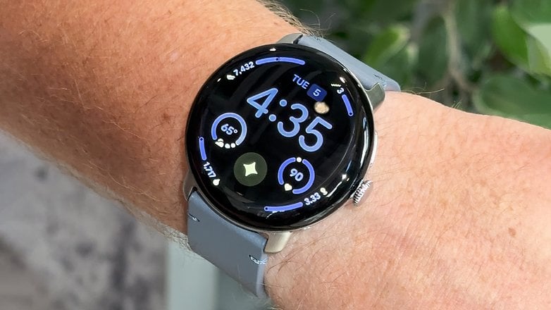 Eine Google Pixel Watch 4 zeigt die Uhrzeit 4:35 und verschiedene Gesundheitsdaten am Handgelenk an.