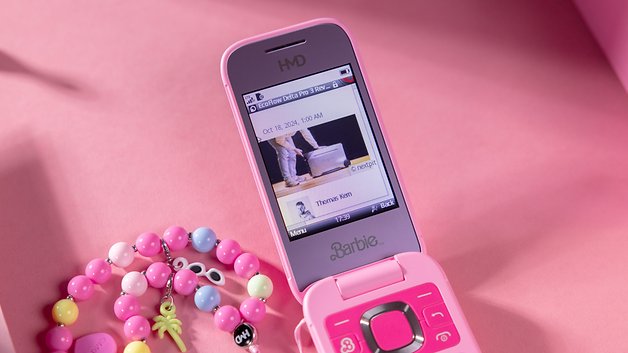 A pink Barbie HMD phone displaying a message with a colorful beaded bracelet beside.