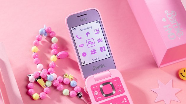 A pink Barbie HMD phone with a messaging screen and colorful bead accessories on a pink background.