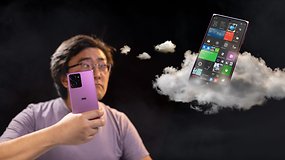 Une personne tenant un smartphone violet avec un nuage affichant une interface d'application colorée en arrière-plan.