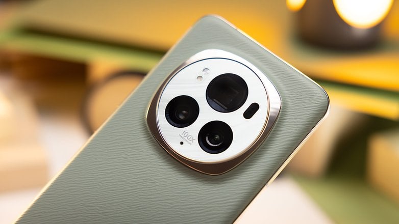 Eine Nahaufnahme des kreisförmigen Kameramoduls auf der Rückseite eines grünen Smartphones, das drei Kameraobjektive und den Text „100x“ zeigt, was auf eine hohe Zoomfähigkeit hindeutet.