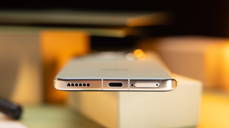 Gros plan sur le bord inférieur d'un smartphone, montrant son port USB-C, la grille du haut-parleur et un plateau de carte SIM.