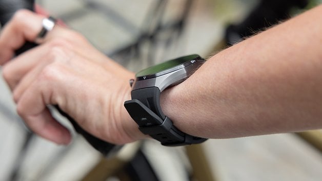 A close-up of a Huawei Watch GT 6 Pro on a person's wrist while holding a bicycle handlebar.