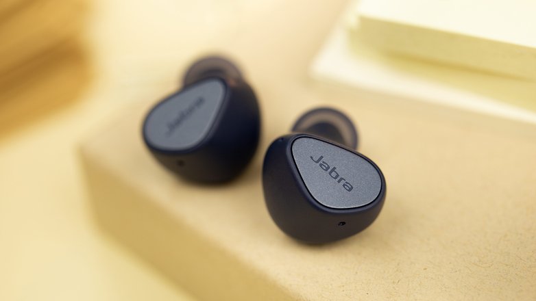 Les Jabra Elite 4 posés à plat et vus de face avec un aperçu des boutons physiques de chaque écouteur