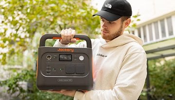 A person holding a Jackery Explorer 1000 portable power station outdoors.