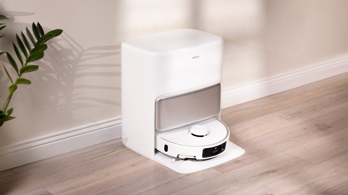 Un dock de robot aspirador Mova P50 Pro Ultra en un interior moderno con suelo de madera y una planta cercana.