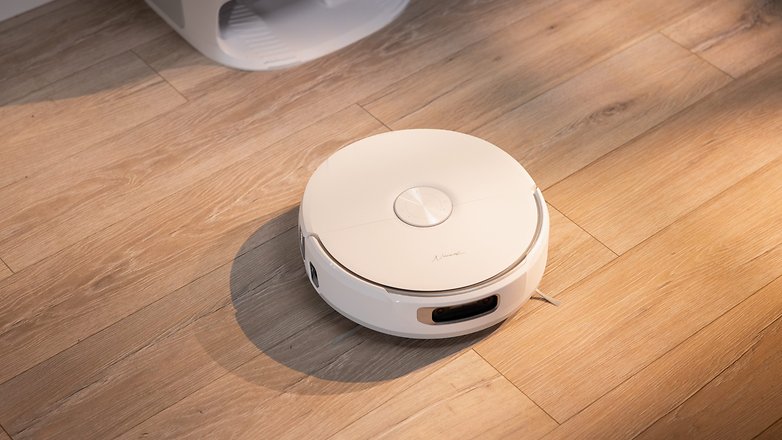 A white robotic vacuum cleaner on a wooden floor. A white robotic vacuum cleaner on a wooden floor.