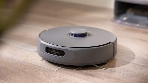 A round, grey robot vacuum cleaner on a wooden floor.