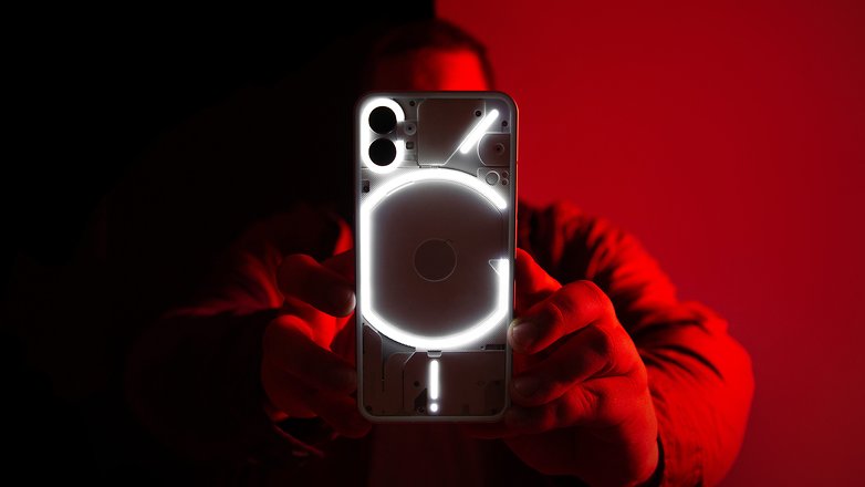 Antoine zeigt im roten Licht stehend die blinkende Rückseite des Nothing Phone (1)