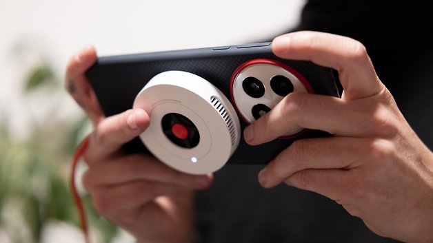 A person holding a OnePlus 13 smartphone with a camera attachment.