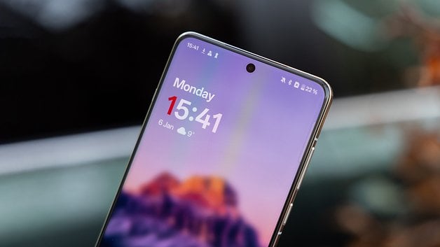 Close-up of a smartphone displaying the time 15:41 on Monday, January 6, with a mountain background.