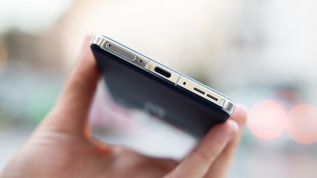 Close-up of a OnePlus 13 smartphone, showing ports and buttons from the top edge.