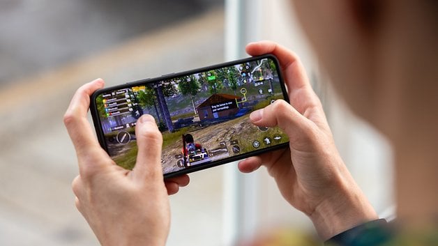 A person playing a mobile game on a smartphone, showcasing the OnePlus 13R's gaming capabilities.