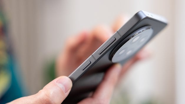 Close-up of a person's hand holding a OnePlus 13R smartphone, showing buttons and camera design.