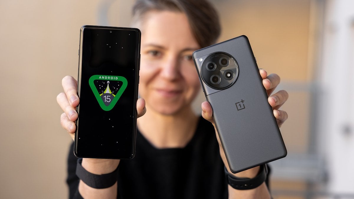 Une personne tient deux smartphones OnePlus, l'un affichant 'ANDROID 15' à l'écran.