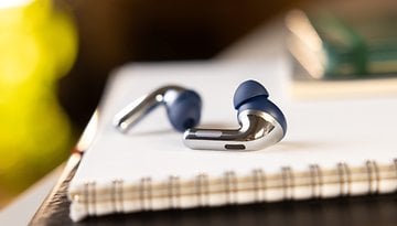Close-up of OnePlus Buds Pro 3 wireless earbuds on a notebook.
