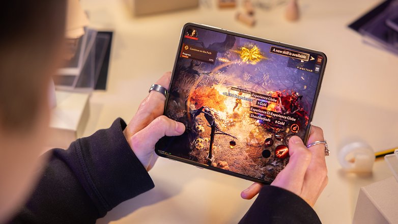 Le OnePlus Fold tenu déplié par Camila dans ses deux mains avec le jeu Diablo Immortal affiché sur le grand écran