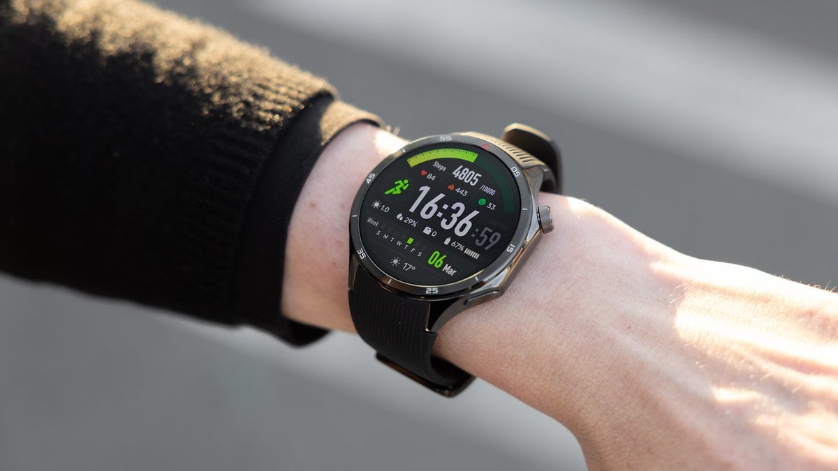 Un poignet affichant une OnePlus Watch 3 avec une interface numérique verte et noire montrant l'heure et des statistiques de fitness.