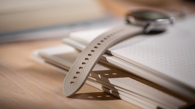 A close-up of a OnePlus Watch 3 (43 mm) on a stack of notebooks.