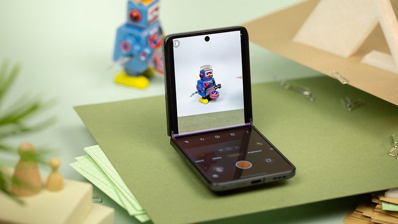 Um smartphone Oppo Find N2 Flip dobrado exibindo uma interface de câmera com um robô de brinquedo à vista.