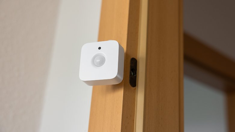 Un capteur de mouvement Philips Hue monté sur un cadre de porte en bois. Un capteur de mouvement Philips Hue monté sur un cadre de porte en bois.