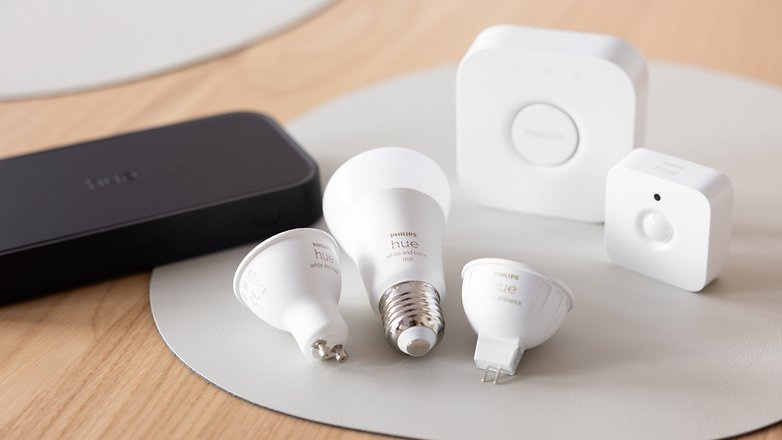 Eine Sammlung von Philips Hue Smarten Glühbirnen und Zubehör auf einer Holzoberfläche.