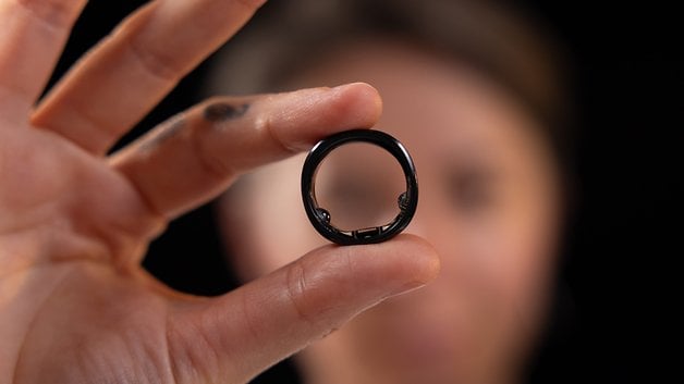 A person holding a RingConn Smart Ring in front of their face against a dark background.