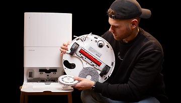 A person displaying the bottom of the Roborock Q Revo MaxV robot vacuum cleaner.