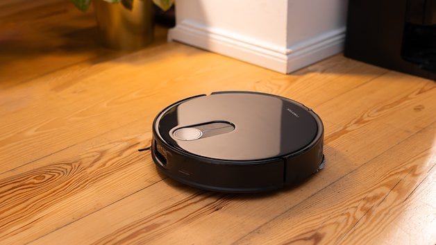 Un aspirateur robot Roborock Qrevo Slim sur un sol en bois.