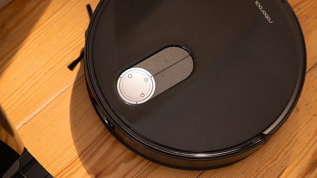 Gros plan d'un aspirateur Roborock Qrevo Slim sur un sol en bois.