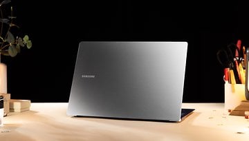 Samsung Galaxy Book 4 Edge Laptop, silber, auf einem Tisch mit Schreibwaren und Pflanzen im schwachen Licht.