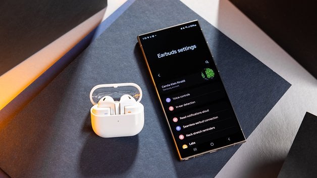 Samsung Galaxy Buds 3 charging case next to a smartphone showing off the earbuds settings.