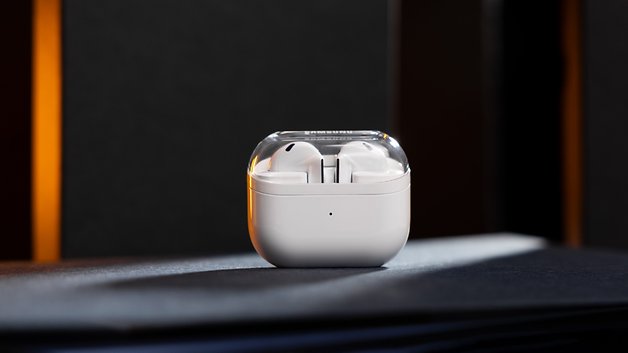 Samsung Galaxy Buds 3 dans leur étui de chargement, présentés sur une surface sombre.