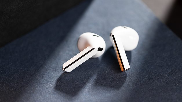 Samsung Galaxy Buds 3 sobre uma superfície escura, mostrando seu design branco.