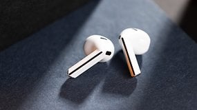 Samsung Galaxy Buds 3 resting on a dark surface, showcasing their sleek white design.