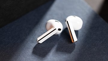 Samsung Galaxy Buds 3 resting on a dark surface, showcasing their sleek white design.