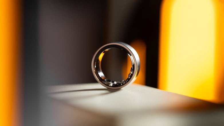 A sleek Samsung Galaxy Ring displayed on a surface with warm lighting in the background.