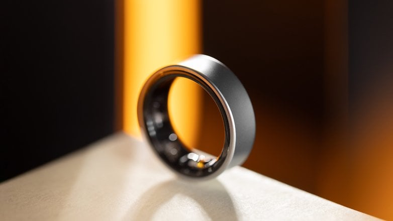 Ein schlanker Samsung Galaxy Ring, der auf einer Oberfläche mit verschwommenem Hintergrund präsentiert wird.