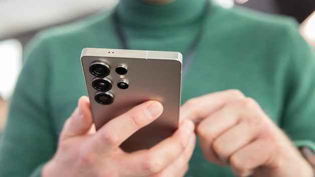 A person holding a Samsung Galaxy S25 smartphone, showing its back design and camera setup.