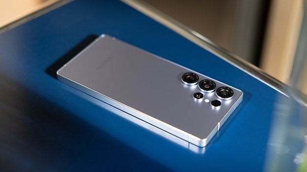 Un smartphone Samsung Galaxy S25 Ultra posé sur une surface bleue.