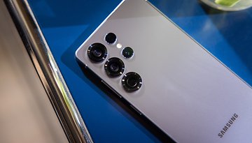 Samsung Galaxy S25 Ultra smartphone with multiple camera lenses on a blue surface.