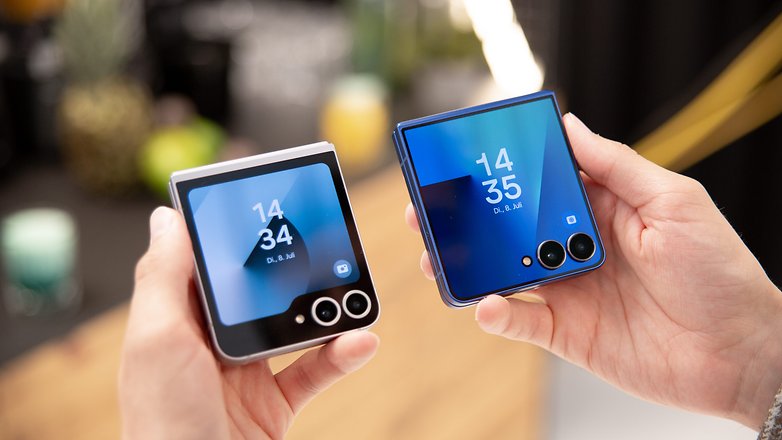 Zwei Samsung Galaxy Z Flip7-Handys nebeneinander, die ihre Bildschirme mit Uhrzeit und Datum zeigen. Zwei Samsung Galaxy Z Flip7-Handys nebeneinander, die ihre Bildschirme mit Uhrzeit und Datum zeigen.
