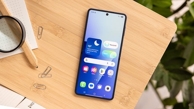 Samsung Galaxy Z Flip7 Smartphone auf einer Holzoberfläche mit angezeigten App-Symbolen auf dem Bildschirm.