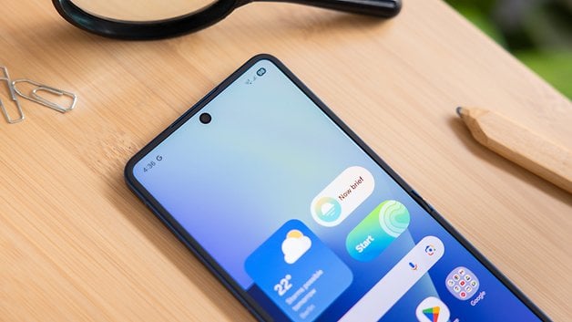 Samsung Galaxy Z Flip7 Smartphone zeigt ein Farbverlauf-Wallpaper und App-Symbole auf einer Holzoberfläche.