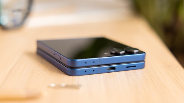 Ein blauer Samsung Galaxy Z Flip7 Smartphone liegt flach auf einer Holzoberfläche.