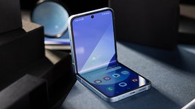 Ein offenes Samsung Galaxy Z Flip 6 Smartphone zeigt seinen Bildschirm mit verschiedenen App-Symbolen und einem blauen Hintergrund.