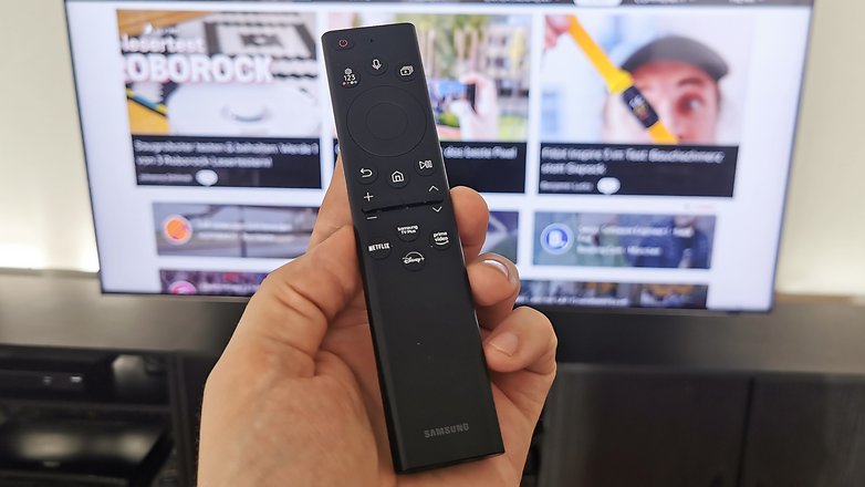 Smart Remote in der Hand gehalten vor dem Samsung TV